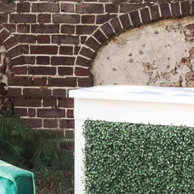 A corner of a bar with a boxwood green facade against a brick background.