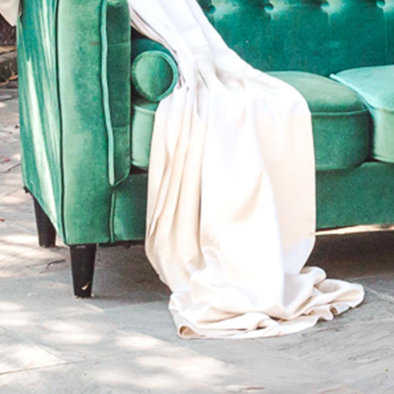 A white linen is draped on the corner of a green rental sofa.