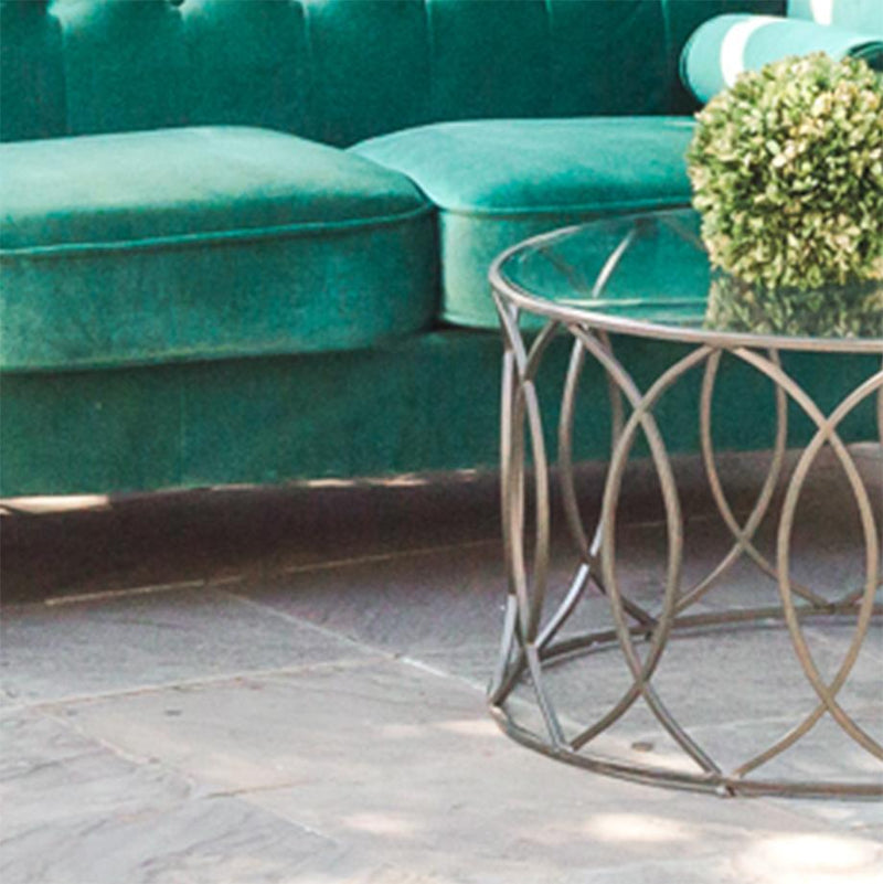A dark green sofa in an outdoor patio setting available for rental.