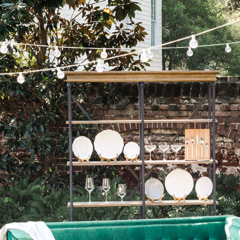 A shelf holding plates and barware set up outdoors.