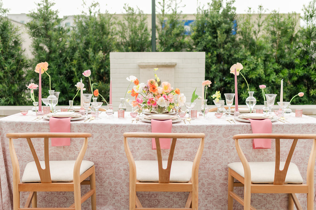 A beautiful outdoor dining table with flowers and pink place settings.